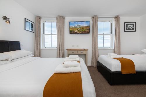 a bedroom with two beds and two windows at Hillside Dunbar in Dunbar