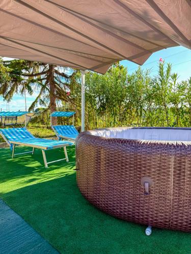 a wicker chair and a bench under an umbrella at Mary Jungle in Porto SantʼElpidio