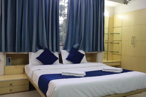 a bedroom with a large bed with blue curtains at Hotel krishnasai in Pune