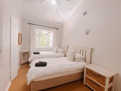 two beds in a room with white walls and a window at Treetops, Amblewood Guesthouse in Kenton on Sea