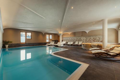 ein großes Schwimmbecken mit Liegestühlen in der Unterkunft Laguscei Dolomites Mountain Hotel in Arabba