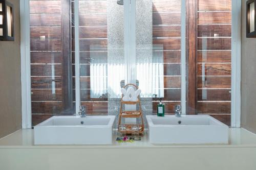 two sinks in a bathroom with two windows at Peach Blossom Resort & Pool Villa - SHA Plus in Kata Beach