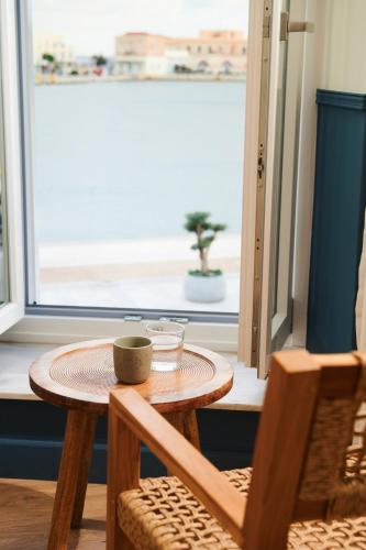 a wooden table with a cup on it next to a window at KALLINO Island Suites in Ermoupoli