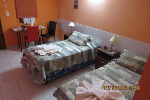 Habitación de hotel con 2 camas y mesa con silla en Hosteria Kaiken Gregores, en Gobernador Gregores
