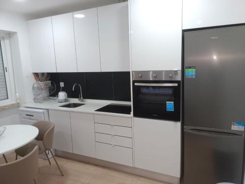 a kitchen with white cabinets and a stainless steel refrigerator at Apartamento Cassoma in Amadora