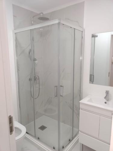 a white bathroom with a shower and a sink at Apartamento Cassoma in Amadora