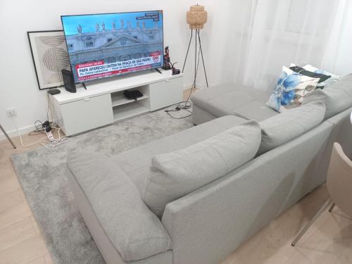 a living room with a couch and a flat screen tv at Apartamento Cassoma in Amadora
