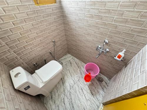 a bathroom with a toilet and a pink bucket at Delight Homestay Gulmarg in Gulmarg