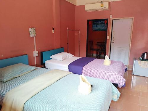 three beds in a room with red walls at Panngernpanthong inn resort in Ban Nong Chaeng