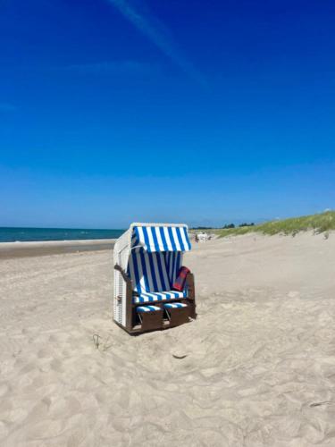 a blue and white beach chair sitting on the beach at "Strandhus Fink" in Dierhagen