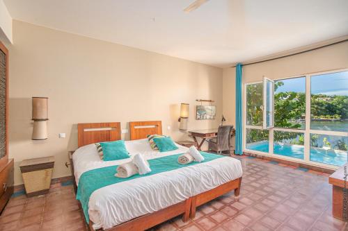 a bedroom with a bed and a large window at Villa Les Agaves front de mer in Le François