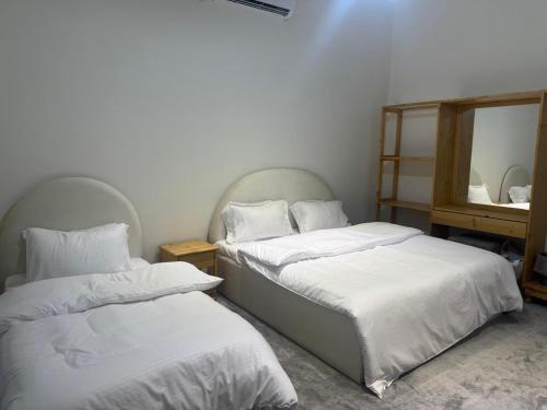 two beds in a room with a mirror at Al REEM Farm house khorfacan in Sabkhah
