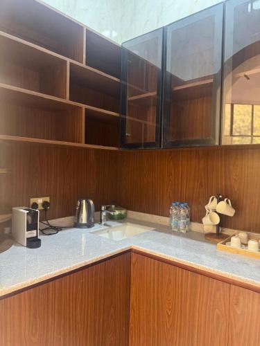 a kitchen with wooden cabinets and a counter top at Al REEM Farm house khorfacan in Sabkhah