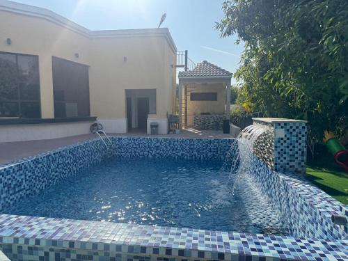a swimming pool with a water feature in front of a house at Al REEM Farm house khorfacan in Sabkhah