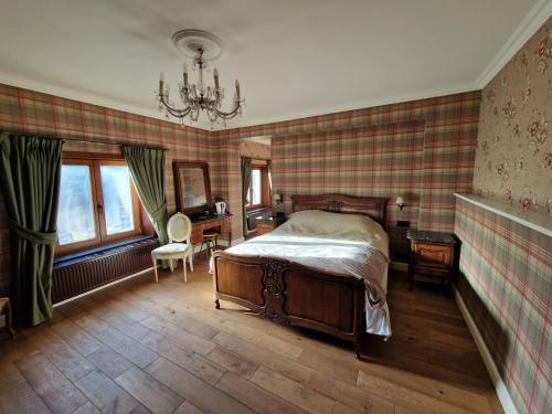 a bedroom with a bed and a chandelier at L'auberge Beauraing in Baronville