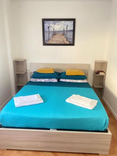 a bedroom with a large blue bed with towels on it at Granaretto 27 in Palidoro