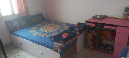 a small bedroom with a bed and a desk at Raina's Home in Bhuj