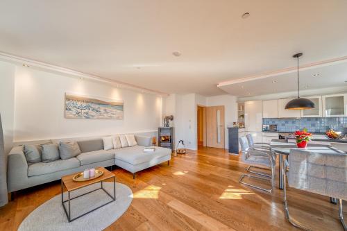 a living room with a couch and a kitchen at Lüftenblick - 2 Ferienwohnungen am Starnberger See, mit Terrasse oder Balkon, Weitblick, Sauna, Kamin, E-Ladestation in Berg am Starnberger See