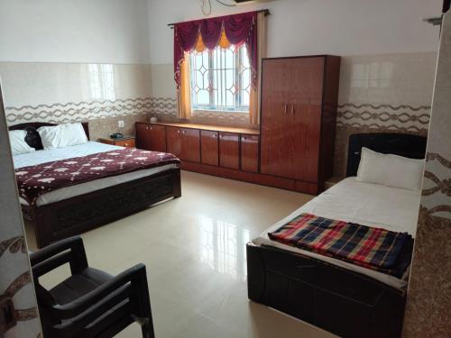 a bedroom with two beds and a chair and a window at R R Paradaise in Pūtalapattu