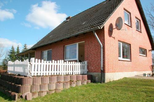 a red brick house with a white picket fence at Ferienhaus Ostsee in Rabenkirchen-Faulück
