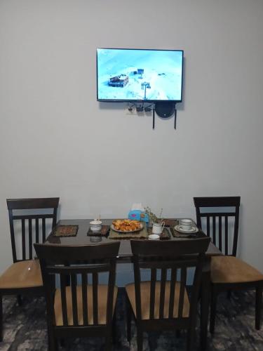 a dining table with chairs and a tv on the wall at Eghipatrush Guesthouse in Aparan