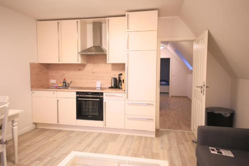 a kitchen with white cabinets and an open door at Schleiblick App 5 in Rabenkirchen-Faulück