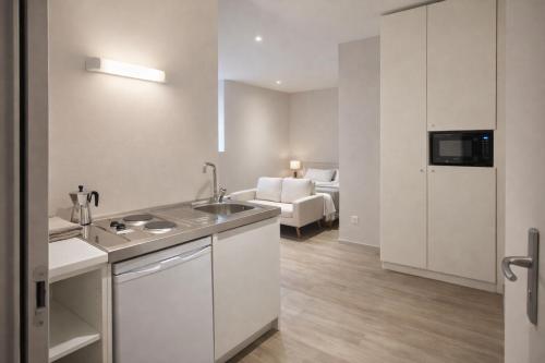 a kitchen with a sink and a room with a bed at Hôtel des Thermes in Bourbon-Lancy