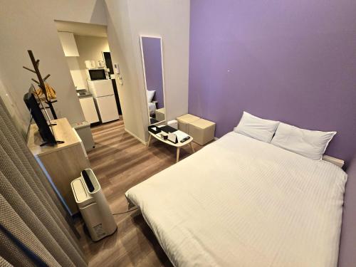 a bedroom with a white bed and a purple wall at Comfort CUBE PHOENIX Yakuin in Susakiuramachi