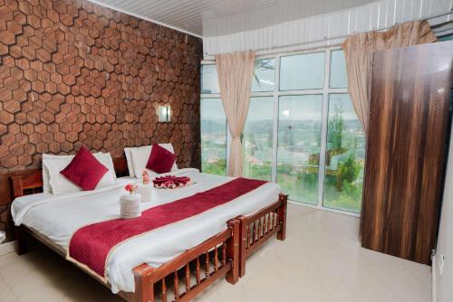 a bedroom with a large bed and a large window at Tulips Resorts - Elkhill in Ooty