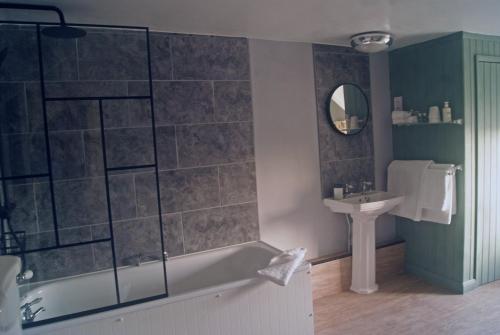 a bathroom with a bath tub and a sink at The Old Smithy Bed & Breakfast in Clovelly