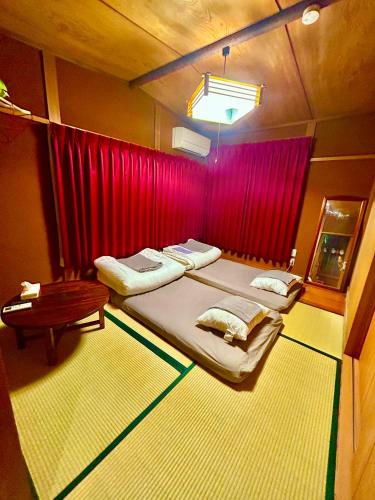 a bedroom with two beds and a red curtain at Guesthouse Kuku Kawagoe in Kawagoe