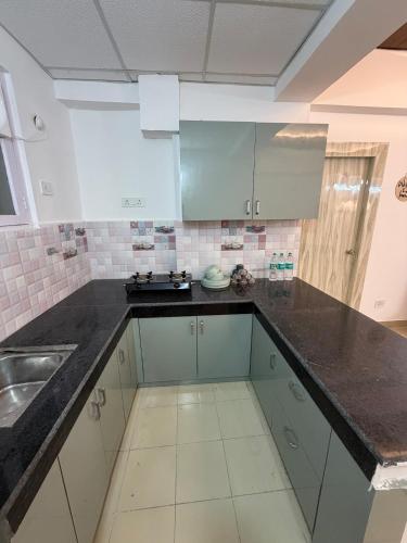 a kitchen with white cabinets and black counter tops at Shiva Stays - Make yourself at home in Lucknow
