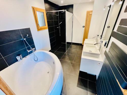 a bathroom with a tub and two sinks and a shower at La lisière romantique in Granges-Aumontzey