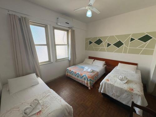 a room with two beds and two windows at Grande Hotel Torres in Torres