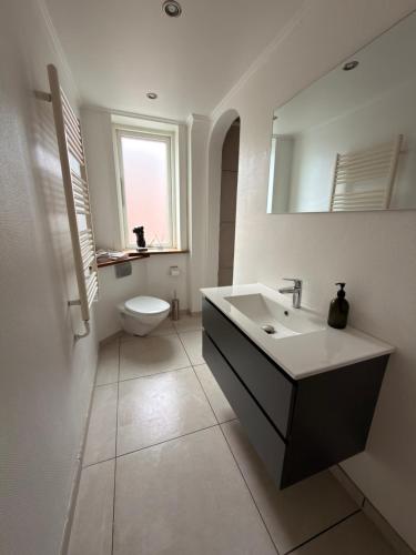 a white bathroom with a sink and a toilet at Central lejlighed i Herning in Herning