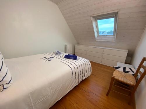 a bedroom with a bed and a window and a chair at Les mouettes rieuses in Telgruc-sur-Mer