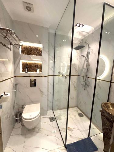 a bathroom with a toilet and a glass shower at Royal Suite Hotel - Nasr City, Cairo in Cairo