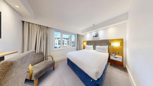 a hotel room with a bed and a chair at Holiday Inn Kenilworth - Warwick by IHG in Kenilworth