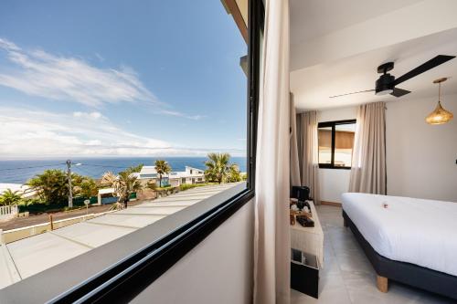 a bedroom with a large window with a view of the ocean at Villa de Luxe avec Piscine privée chauffée-3 Chambres-Sud Sauvage in Petite Île