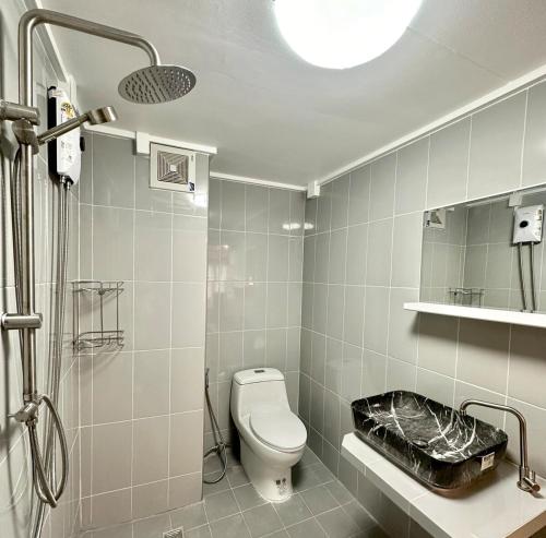 a white bathroom with a toilet and a shower at Jumboboom in Ban Bang Phang