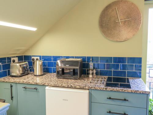 a kitchen with blue tiles and a clock on the wall at Golden Valley View in Stroud