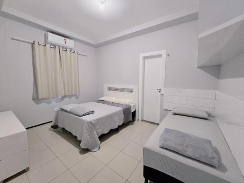 a white bedroom with two beds and a window at Casa de praia in São Luís