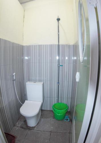 a bathroom with a toilet and a green bucket at Wisma Dahlia in Maumere