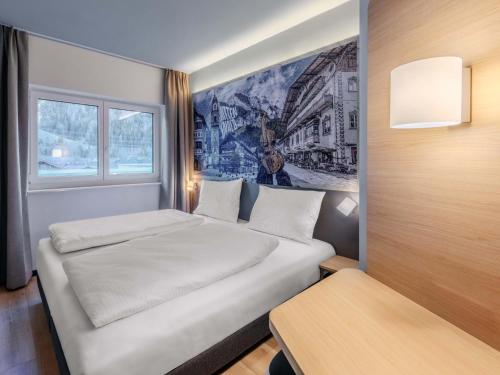 a bedroom with a white bed and a window at B&B HOTEL Mittenwald in Mittenwald