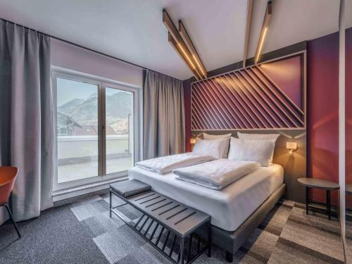 a bedroom with a large bed and a large window at B&B HOTEL Mittenwald in Mittenwald