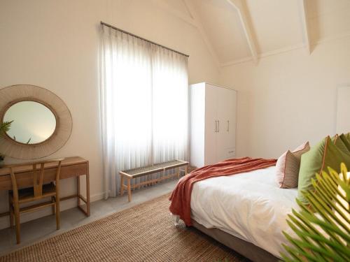 a bedroom with a bed and a desk and a mirror at Cornercade | Unit 1 in Hermanus