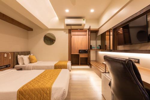 a hotel room with two beds and a flat screen tv at Hotel Olten in Mumbai