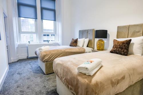 two beds in a room with two windows and a room with two beds at Cambridge Apartment in Glasgow