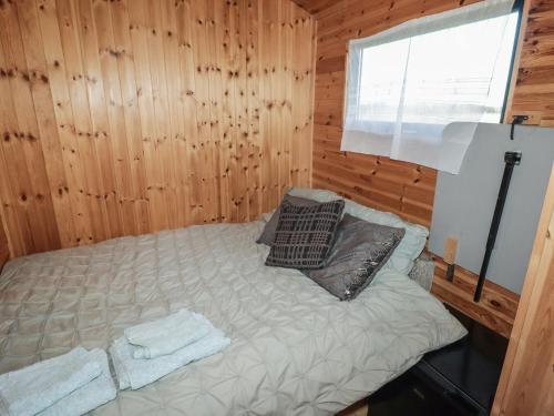 a bed in a wooden room with a window at Rhosgranog Shepherds Hut in Haverfordwest