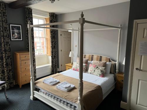 a bedroom with a canopy bed with towels on it at The Silk House in Leek